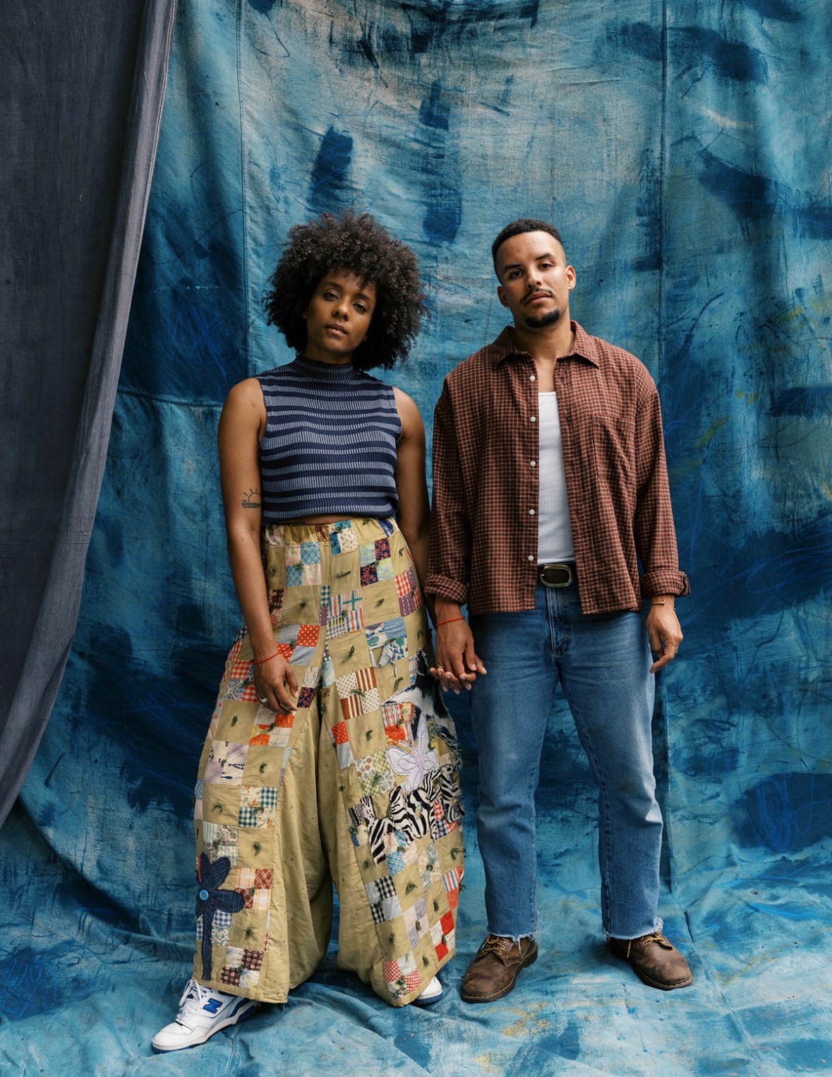 Portrait of artists Tavior and Zandy Mowry standing together against a hand painted indigo backdrop
